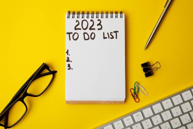 2023 numaralı listeyi yapmak için. Sarı arka planda not defteri ve cep telefonu. iş kavramı