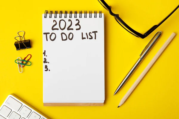 stock image To do list 2023. Notepad and mobile phone on a yellow background. business concept