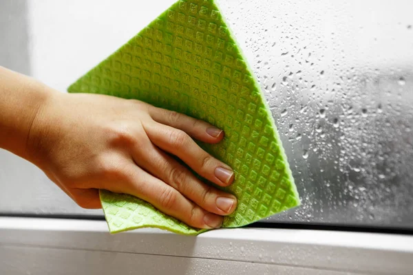 家の中の湿度が高い 手で部屋のプラスチック窓ガラスから結露水を拭き取ります 家の水分 — ストック写真
