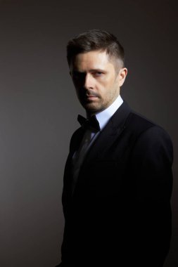 Siyah arka planda siyah süitteki adam.