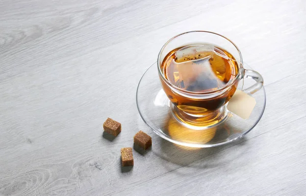 Cup of Tea and teabag, sugar, on a light wooden background