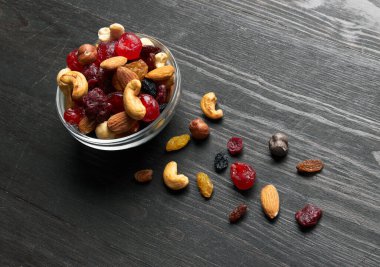 Bir kase fındık ve kurutulmuş meyve. Fındık, ceviz, kaju, badem, kuru üzüm, kızılcık, kiraz, ahşap arka planda..
