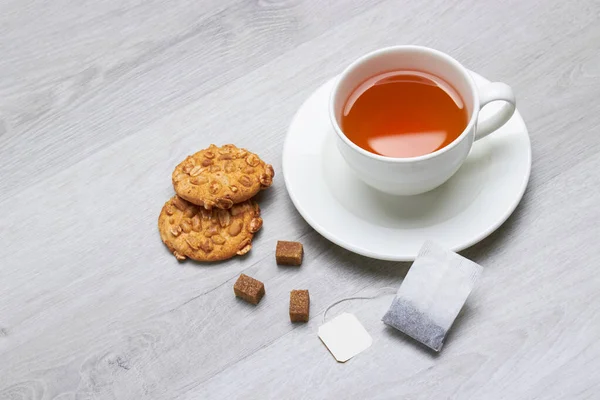 茶とティーバッグ クッキー 砂糖のカップ 軽い木製の背景 — ストック写真