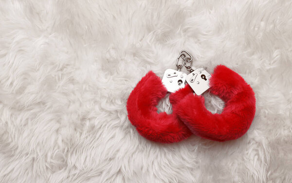 Red sexy fluffy handcuffs on a fur background