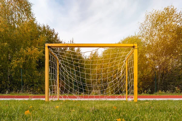 Front view of a small yellow football goals in a stadium during autumn season. Football goals for kids training.