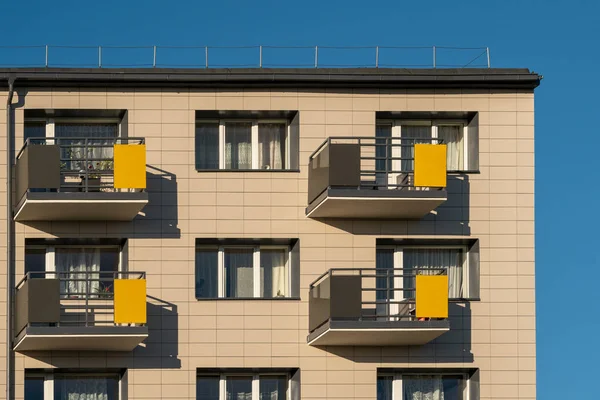 Top part of block of flats building with blue sky. Architecture abstract.Modern Facade Building with Yellow Balconies.