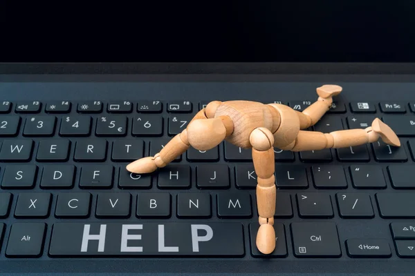 在线帮助按钮 木制假人试图在计算机键盘上达到Help按钮 — 图库照片