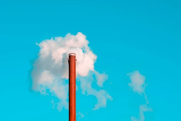 World pollution concept. Factory chimney blowing smoke from pipe in blue sky background during winter time