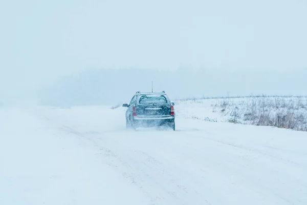 The car is driving on a winter road in a blizzard. Traffic and vehicles in a snow storm in winter.