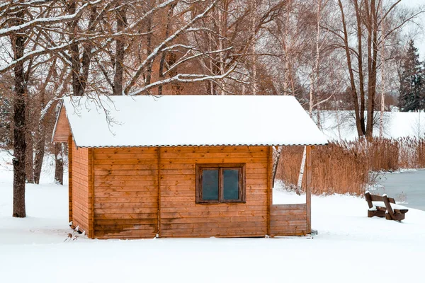 Winter landscape with a small wooden lodge in the nature