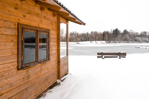 Winter landscape with a small wooden lodge in the nature at the frozen lake