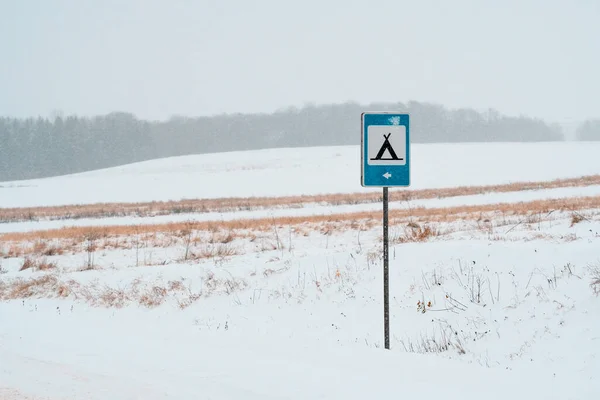 Snow covered camping sign at road in a heavy snow.Camping in winter season.