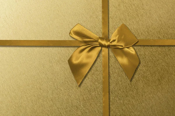 Gold ribbon with bow on a golden background. Luxury shiny gold gift box.