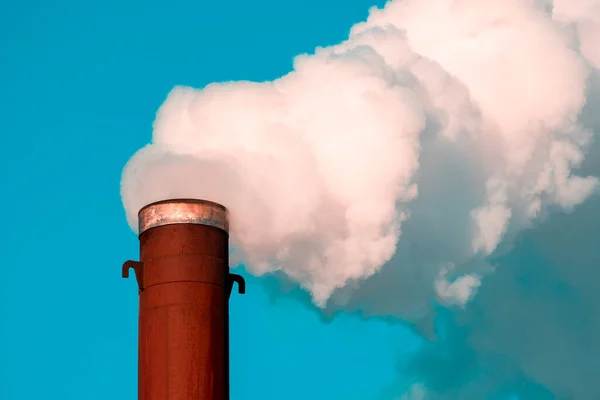 Pipe and smoke on sky background.Polluting air with white smoke from industrial chimney outdoors. CO2 emissions.
