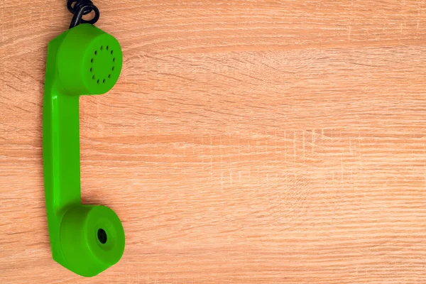 Vintage telephone handset. Old green telephone receiver hanging on the wooden background. Copy space.