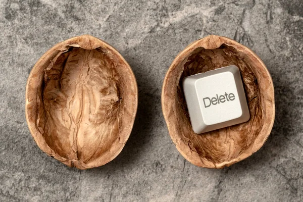 Opened walnut shell with a DELETE key of computer keyboard. Conceptual image.