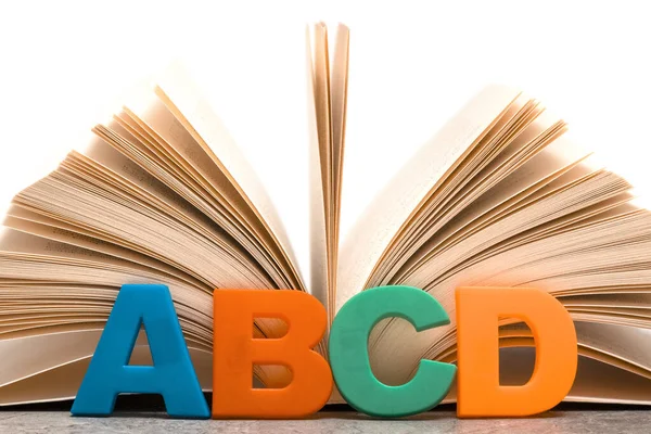 Alphabet letters ABCD and open book. Education concept.