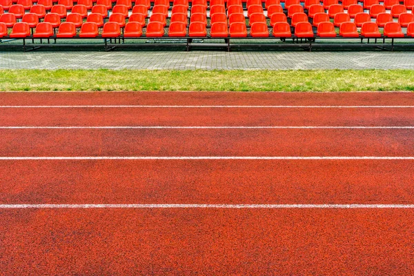 Empty running track and red plastic chairs on a sports stadium