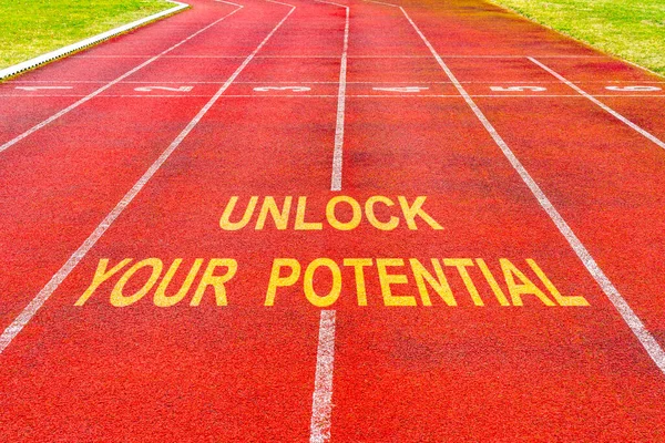 Motivational quote written on red rubberized running track: Unlock Your Potential