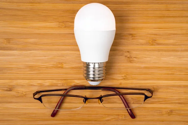 Kreativní Koncepce Myšlení Zářivou Žárovkou Brýlemi Dřevěném Pozadí Obchodní Koncept — Stock fotografie