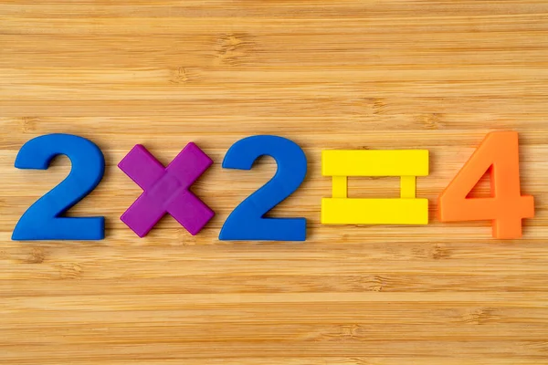 木制桌子上有彩色塑料数字的简单乘法公式 — 图库照片