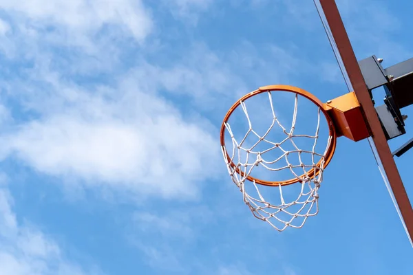 Basketball hoop against a blue sky from a low angle.Low angle shot of basketball hoop on sunny day outside at basketball court