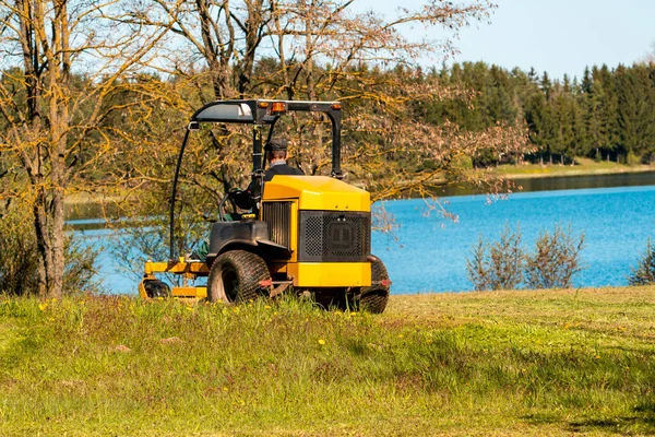 夏の公園の芝刈り機の男 バックビュー トラクター芝刈り機の草を切る — ストック写真