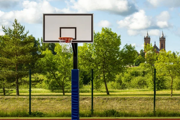 An outdoor community basketball court with a natural landscape and Church steeples