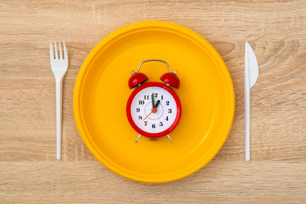 目覚まし時計付きの使い捨てイエロープレート 夕食の時間 — ストック写真