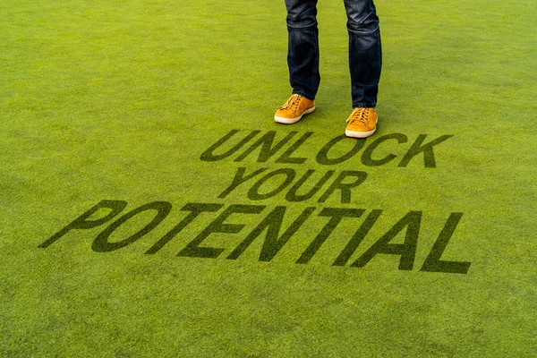 緑の合成芝の上に立つ男は やる気の引用と書かれた あなたの潜在的なロックを解除 — ストック写真