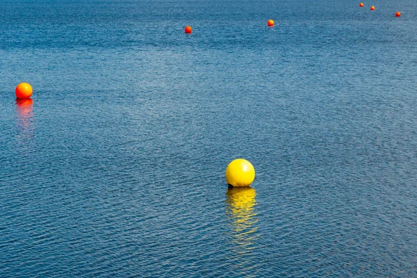 蓝色湖水中的黄色和橙色浮标可以充气 水的安全 — 图库照片