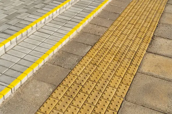 盲目のハンディキャップのためのタクタイル舗装の黄色いブロック ブロック 視覚障害者のための触覚タイル 階段に位置するテクスチャされた地上表面指標 ストックフォト