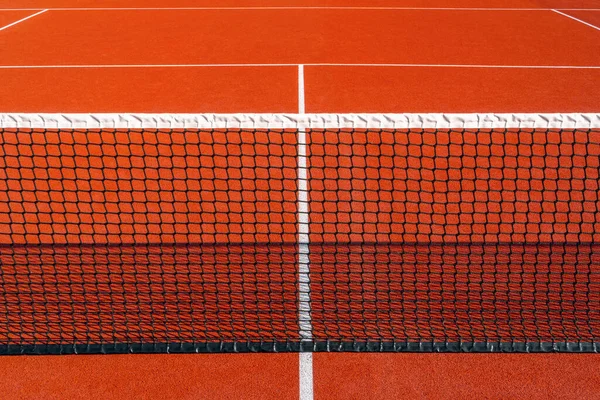 屋外の赤い遊び場の上の黒いテニス網 テニス網およびライン ロイヤリティフリーのストック写真