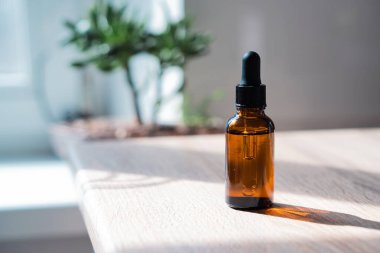 Kahverengi kehribar rengi serum serumu yağ düşürücü şişesi ve beyaz havlu. Masa maketi, kozmetik konteynır gerçek iç mekan, bakım ürünü şablonu.