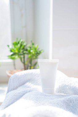 Beyaz krem tüp ve havlu gerçek odada iç mekan modelleme, güzellik ve bakım ürünleri tasarıma hazır şablon, fotokopi alanı olan kozmetik kap
