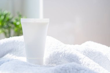Beyaz krem tüp ve havlu gerçek odada iç mekan modelleme, güzellik ve bakım ürünleri tasarıma hazır şablon, fotokopi alanı olan kozmetik kap