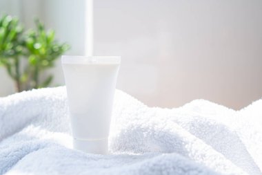 Beyaz krem tüp ve havlu gerçek odada iç mekan modelleme, güzellik ve bakım ürünleri tasarıma hazır şablon, fotokopi alanı olan kozmetik kap