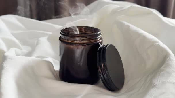 Doofde Kaars Amberkleurige Glazen Pot Met Deksel Witte Linnen Achtergrond — Stockvideo