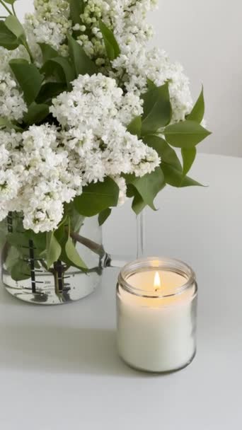 Burning Candle Clear Glass Jar White Lilac Bouquet White Table — Stock Video