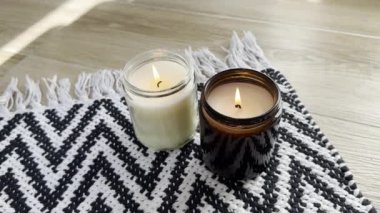 Yerde siyah beyaz halı üzerinde cam kavanozda yanan iki mum, gerçek iç dekorasyon yakın plan.