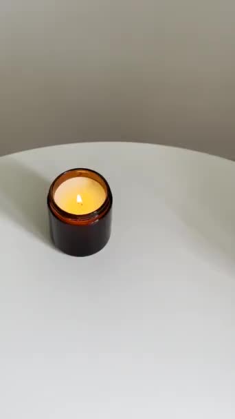 男人的手把燃烧的蜡烛放在白色桌子上的玻璃瓶里 室内装饰容器里的蜡烛视频模拟特写镜头 — 图库视频影像