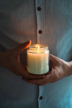 Elinde yanan bir mum tutan adam, mum kavanozlu zarif genç adam, yakın çekim, meditasyon ve farkındalık konsepti.