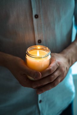 Elinde yanan bir mum tutan adam, mum kavanozlu zarif genç adam, yakın çekim, meditasyon ve farkındalık konsepti.