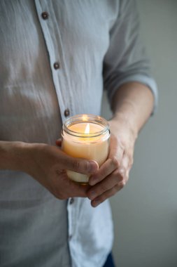 Elinde yanan bir mum tutan adam, mum kavanozlu zarif genç adam, yakın çekim, meditasyon ve farkındalık konsepti.
