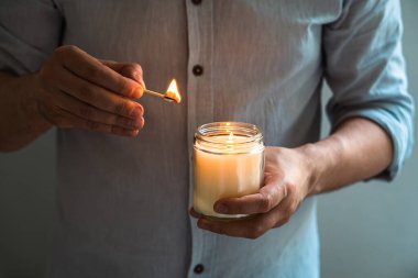 Elinde yanan bir mum tutan adam, mum kavanozlu zarif genç adam, yakın çekim, meditasyon ve farkındalık konsepti.