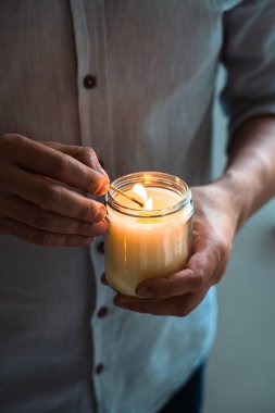 Elinde yanan bir mum tutan adam, mum kavanozlu zarif genç adam, yakın çekim, meditasyon ve farkındalık konsepti.