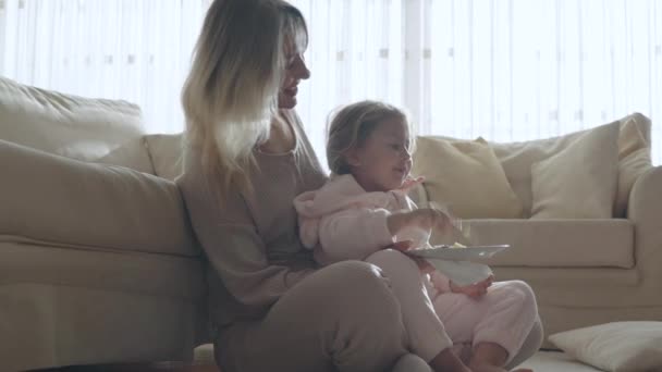 Mom Feeds Her Little Daughter While Sitting Floor Leaning Sofa — Stock Video