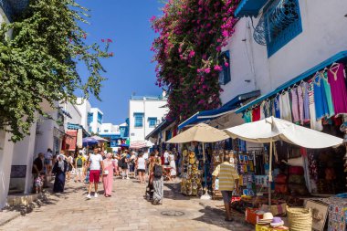 Sidi Bou Said, Kartaca, Tunus - 27 Ağustos 2022: Şehir merkezinde yürüyen insanlar. Kasaba turistik bir yerdir ve mavi ve beyazı yoğun kullanımıyla ünlüdür..