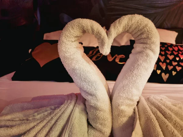 Towels folded in swan shape on bed sheet