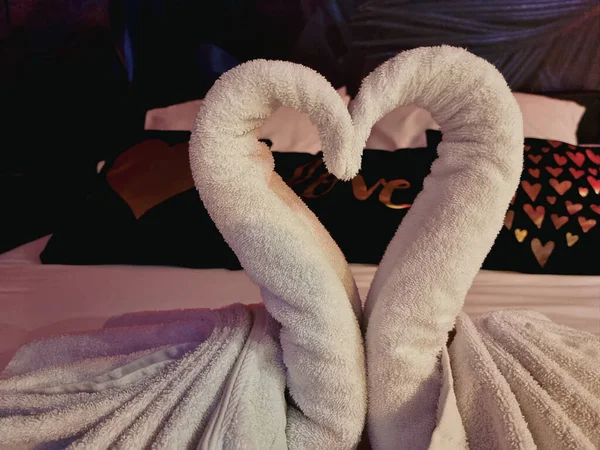 Towels folded in swan shape on bed sheet